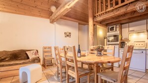 A cozy wooden-floored living room with a dining table, chairs, and a sofa. - LA Pastorale - LE Genepi (VAL CENIS)