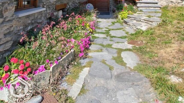 A stone building with wooden balconies and a stone staircase leading to the entrance. - LA Pastorale - LE Genepi (VAL CENIS)