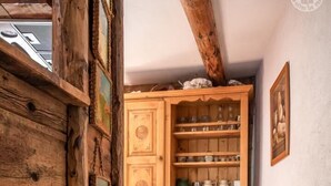 A wooden cabinet with glassware and dishes, a tiled floor, and a rustic ceiling beam. - LES Pinatsotes - Aussois (AUSSOIS)
