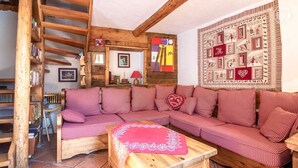 A cozy living room with a checkered sofa, a wooden coffee table, and a bookshelf filled with books. - LES Pinatsotes - Aussois (AUSSOIS)