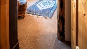 A cozy room with a wooden door, a small table, a sofa, and a patterned rug. - LES Pinatsotes - Aussois (AUSSOIS)