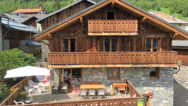 A wooden chalet with a balcony, stone walls, and outdoor seating. - LES Cabris - Meribel-les-allues (MERIBEL LES ALLUES)