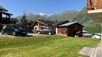 Un quartier résidentiel avec deux maisons, une voiture et une montagne en arrière-plan.