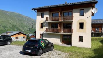 Un immeuble à plusieurs étages doté de balcons, d’une antenne parabolique et d’une voiture garée.