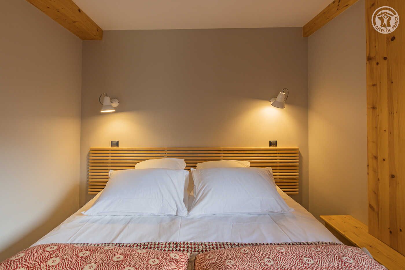 A bed with white linens, two bedside lamps, and a wooden headboard.