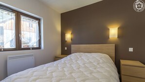 Ein Schlafzimmer mit einem großen Bett, zwei Nachttischen, einem Heizkörper und zwei Wandlampen.