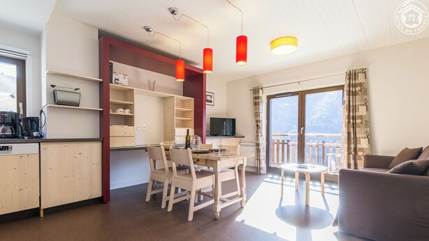 Ein modernes Wohnzimmer mit Essbereich, Küche und einem Balkon mit Blick.
