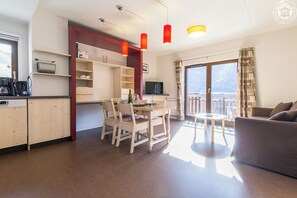 A modern living room with a dining area, a kitchen, and a balcony with a view.