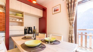 A dining area with a wooden table, two green bowls, wine glasses, and a coffee maker. - LA Lauziere - Montsapey (MONTSAPEY)