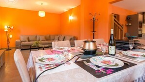 A dining area with a table set for four, a sofa, and a kitchen in the background.