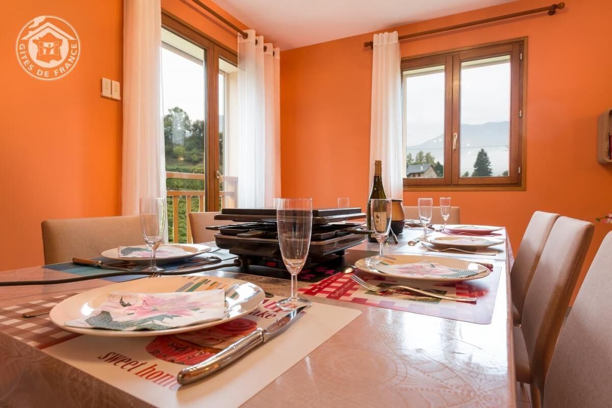 A dining table set with plates, cutlery, and glasses, with a bottle of wine on the table.