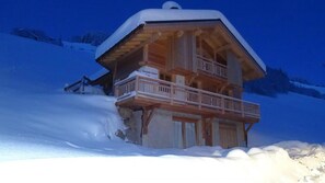 A wooden chalet with a balcony, surrounded by snow.