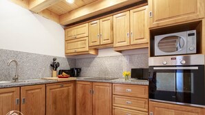 A kitchen with wooden cabinets, granite countertops, a microwave, and an oven.