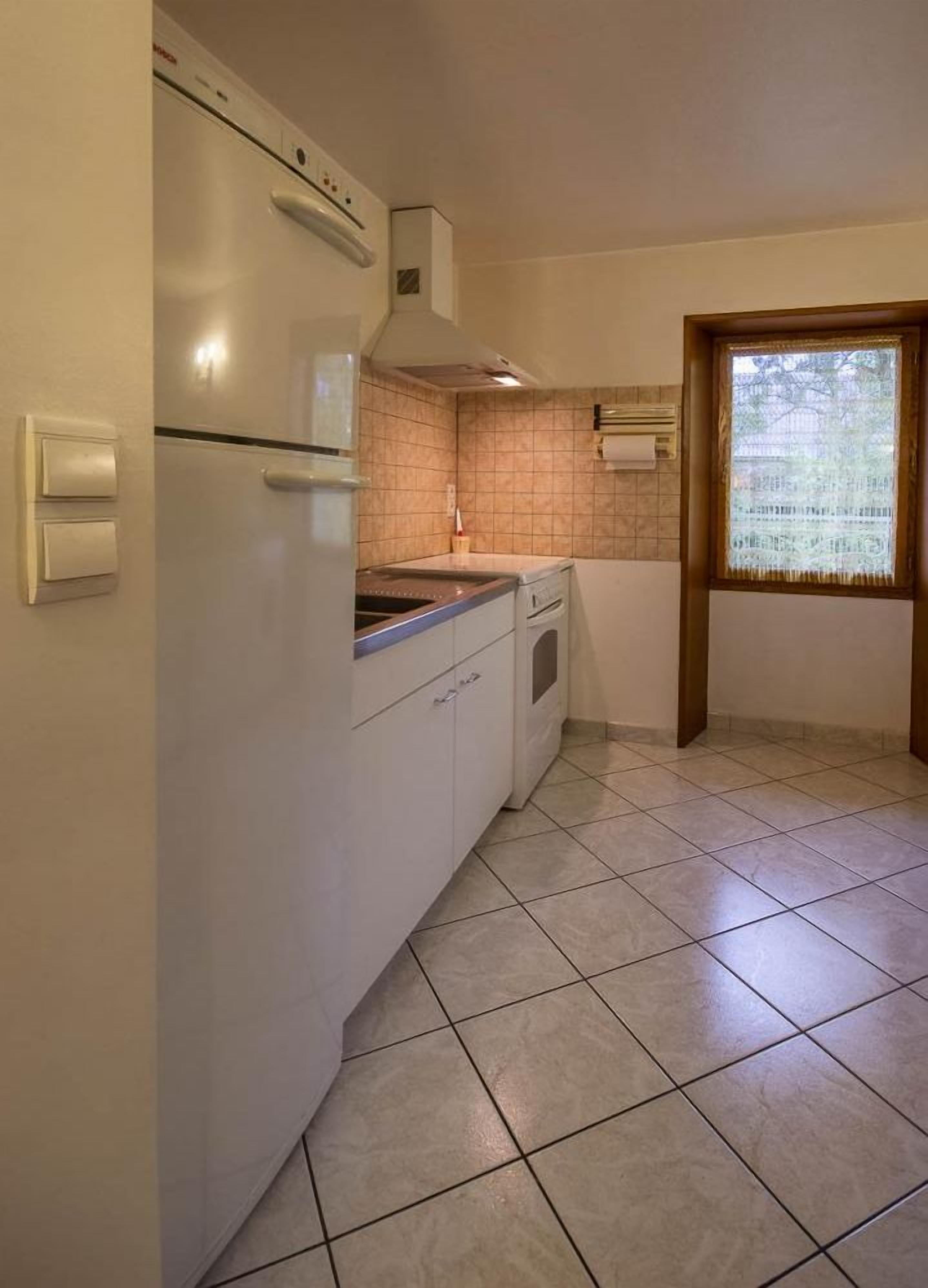 A compact kitchen with white cabinets, a built-in oven, and a window with a view.