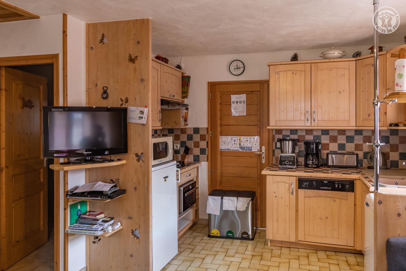 A compact kitchen with wooden cabinets, a microwave, a stove, a sink, and a small refrigerator.