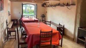 A dining area with a long table covered in red, wooden chairs, and a rustic ceiling with exposed beams. - LE Gite DE Myans - Myans (MYANS)