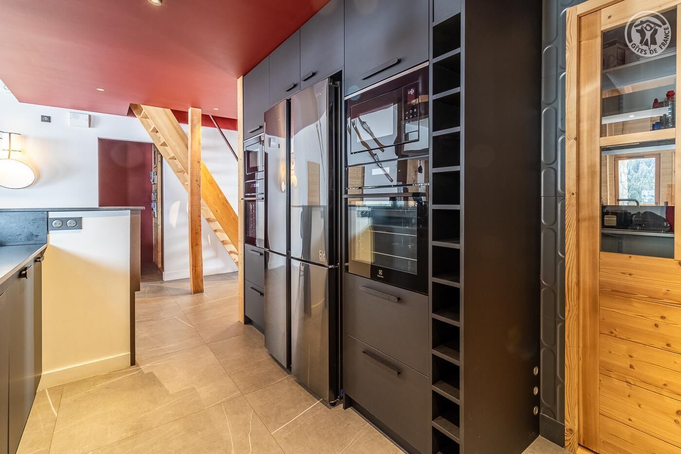 A modern kitchen with a built-in oven, a refrigerator, and a wooden cabinet with glass doors.