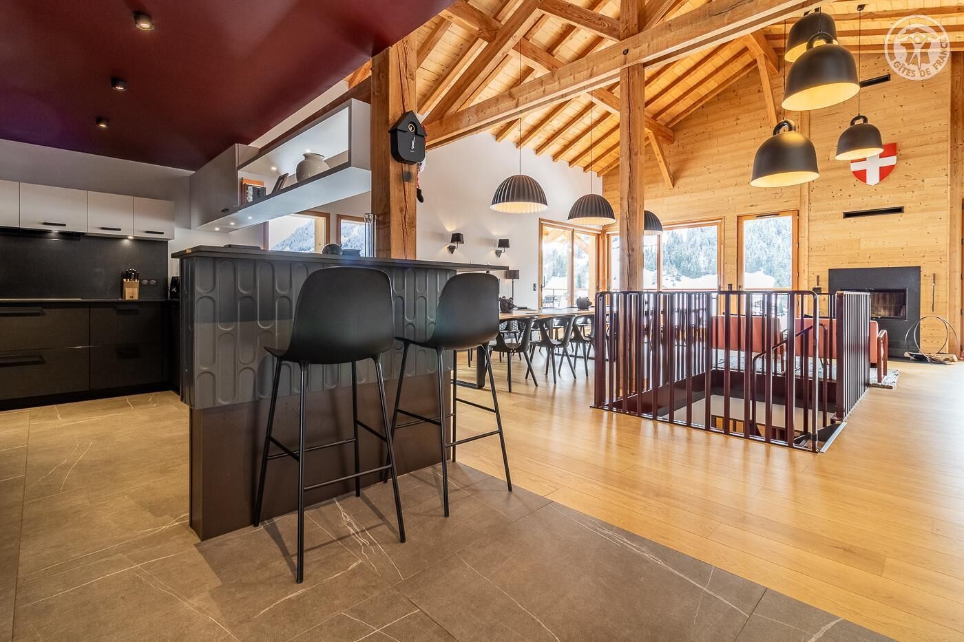 Une cuisine spacieuse avec un coin bar, des poutres en bois et de grandes fenêtres.
