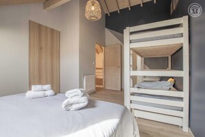 Une chambre avec un lit superposé, une armoire en bois et un luminaire suspendu.
