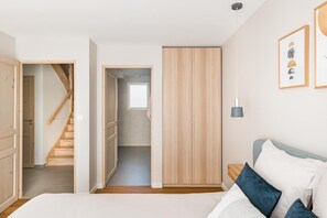 Ein Schlafzimmer mit einem Bett, einem Nachttisch, einem Kleiderschrank und einer Treppe zu einem anderen Raum.