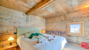 A wooden cabin bedroom with a bed, bedside lamp, window, and a small stool. - Chalet Lidia Ski in-Ski out 50m (Livigno)