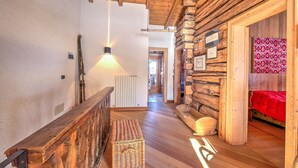 A wooden interior with a staircase, a bench, and a bed with a red blanket. - Chalet Lidia Ski in-Ski out 50m (Livigno)