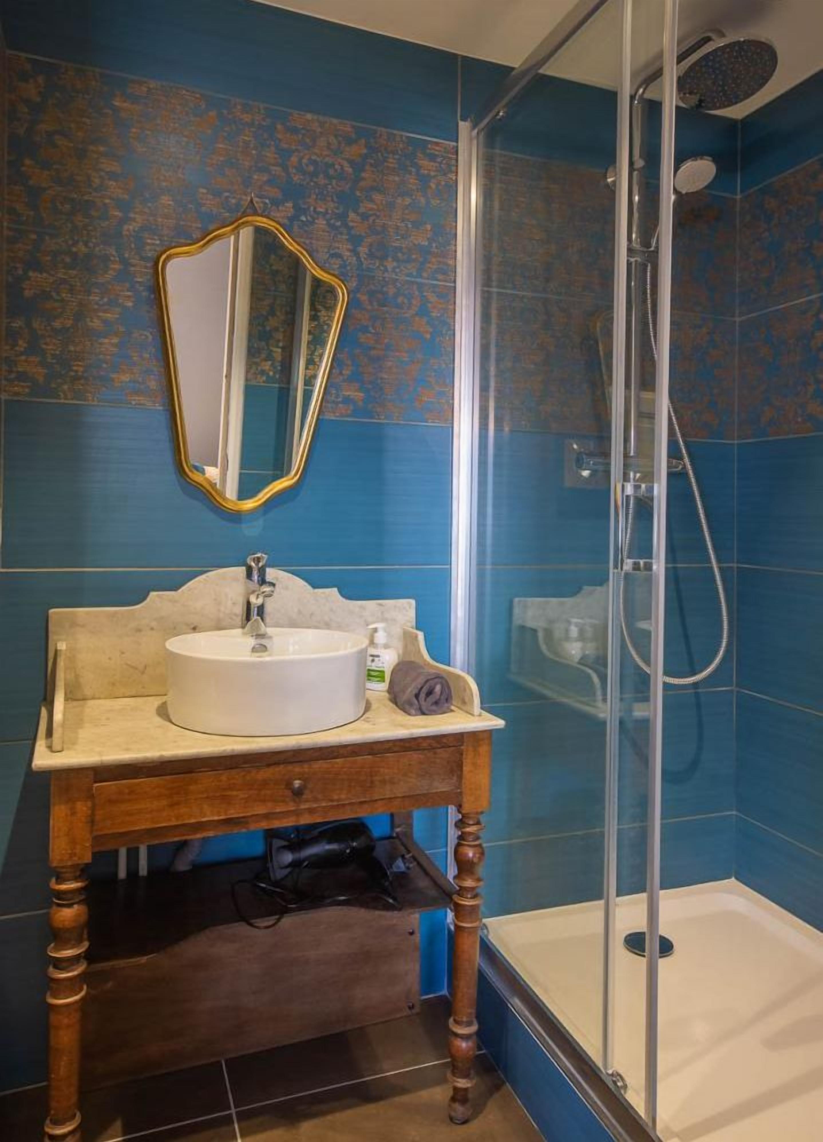 A bathroom with a sink, mirror, and shower.