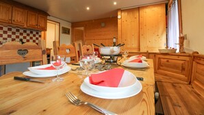 Una mesa de madera para comer con platos, vasos y cubiertos, y un cabecero de madera con forma de corazón detrás.