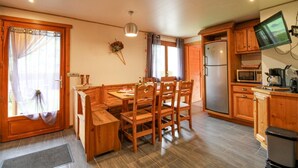 Un comedor acogedor de madera con una mesa y sillas, un refrigerador, un microondas y un televisor en una cocina.