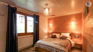 Un dormitorio acogedor con cabecera de madera, cama grande con colcha escocesa y dos lámparas de noche.