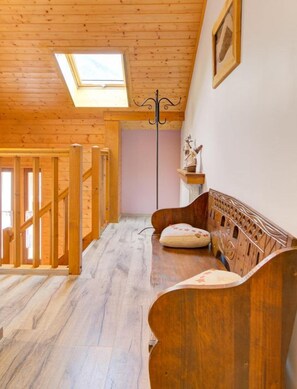 A wooden staircase leading to a loft area with a skylight, a wooden bench, and a small shelf with a statue. - LE Mont Charvin - Flumet (FLUMET)