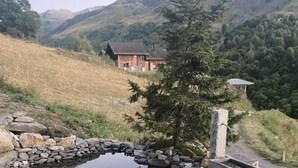 A small pond with a stone bridge, surrounded by grass and a stone structure. - Hislianie - LES Belleville (LES BELLEVILLE)