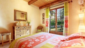 Un dormitorio con cama, cómoda, silla y ventana con cortinas.