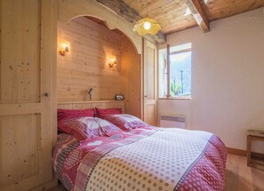 A wooden bedroom with a bed, a window, and a small table. - LE Gite DU Blanchon - Montricher-albanne (MONTRICHER ALBANNE)