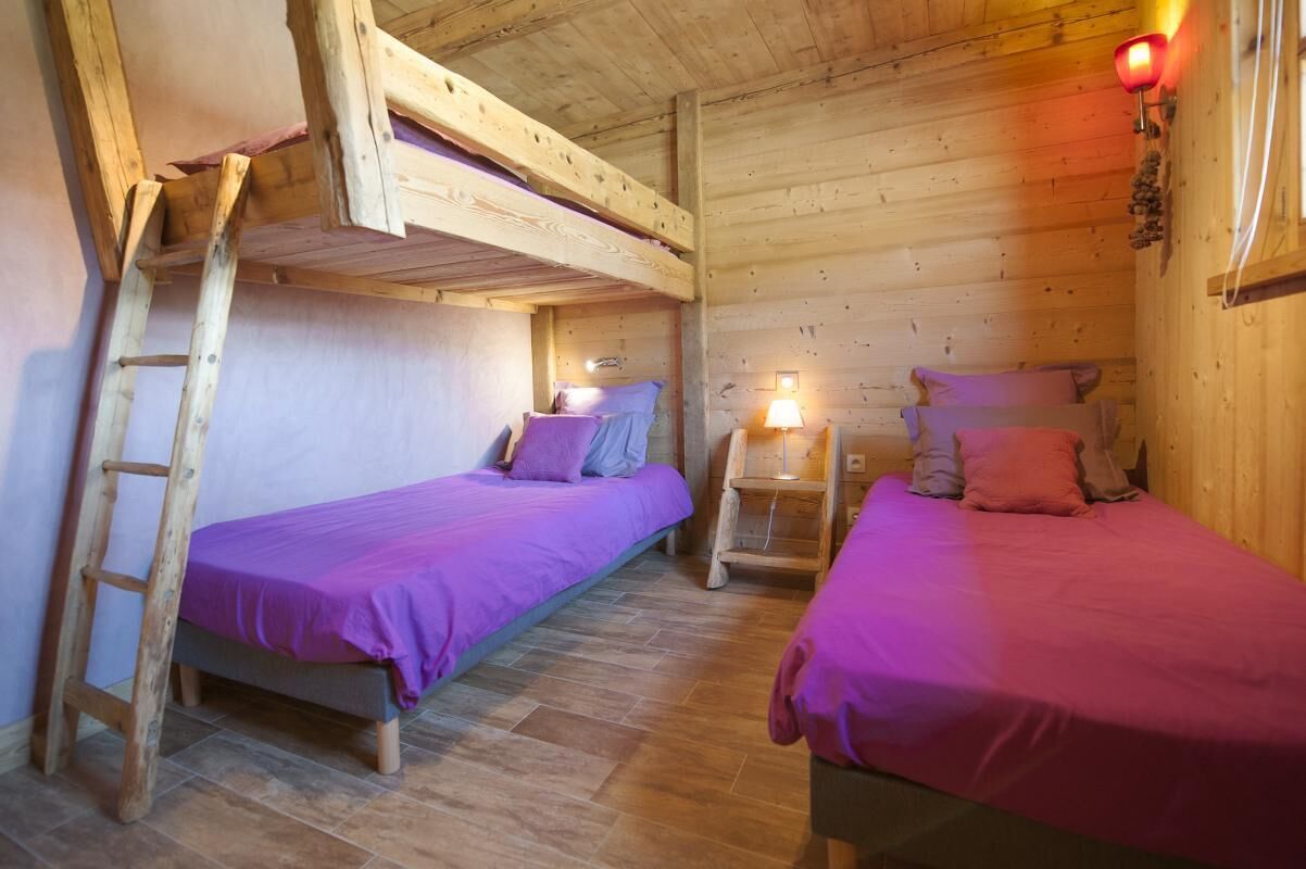 En hytte med to køjesenge, trævægge, en stige og et lille bord med en lampe.