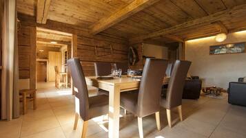 Un coin repas en bois avec une table dressée pour quatre personnes, entourée de chaises.