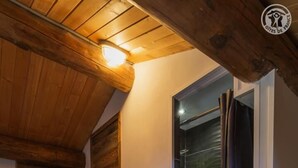 Un intérieur en bois avec un plafond incliné, une porte en bois et une porte vitrée donnant sur une pièce.
