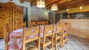 Un coin repas en bois avec des chaises en forme de cœur, une table recouverte d’une nappe à motifs et des luminaires suspendus.