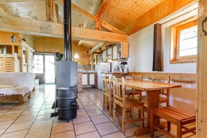 Un intérieur en bois doté d’un système de chauffage central, un coin repas avec des tables et des chaises en bois, et une cuisine équipée d’appareils électroménagers modernes.