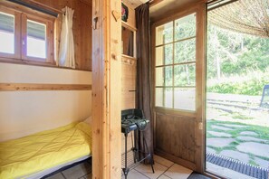 A wooden cabin with a single bed, a small kitchenette, and a large window offering a view of the outdoors. - Pierra Menta - LA Plagne Tarentaise (LA PLAGNE TARENTAISE)