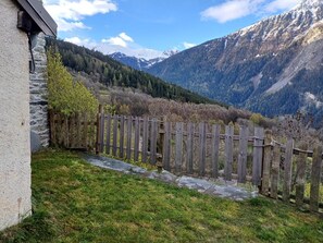 A stone wall, wooden fence, and a grassy area with a mountain backdrop.