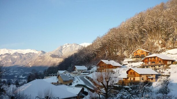 Un pueblo nevado en la montaña con casas de madera y vistas a montañas cubiertas de nieve.
