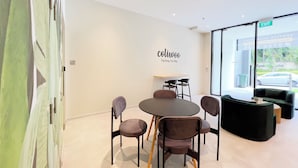 Un intérieur moderne avec une table ronde, quatre chaises, un petit coin bar et une grande fenêtre donnant sur l’extérieur.