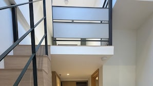 Un appartement moderne doté d’un escalier, d’une cuisine, d’un coin repas et d’un téléviseur fixé au mur.