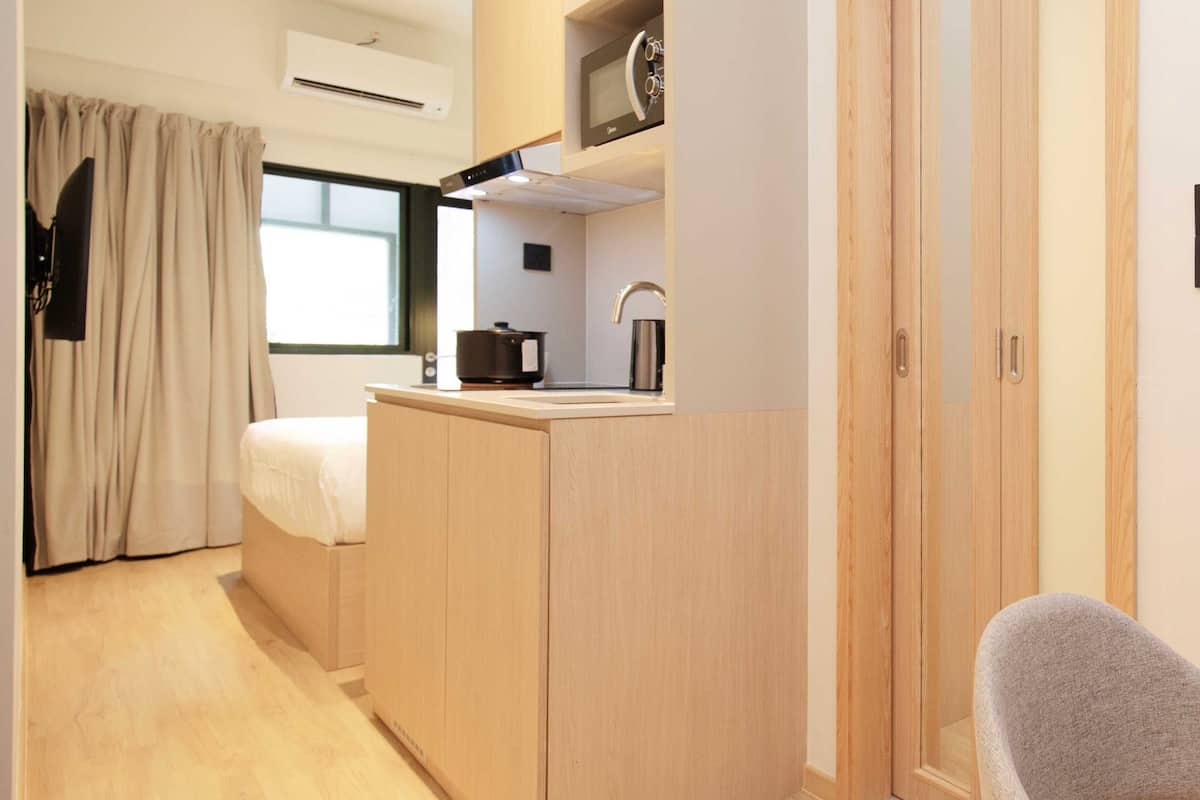 Une petite pièce comprenant un coin cuisine, un lit, une chaise et une armoire.