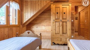 A wooden cabin room with two beds, a wardrobe, and a sloped ceiling. - LA Ferme DES Moulins (VALLOIRE)