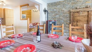 A dining area with a stone wall, wooden furniture, and a fireplace. - LA Ferme DES Moulins (VALLOIRE)