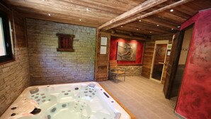 A spa room with a large hot tub, stone walls, and a wooden ceiling. - LA Ferme DES Moulins (VALLOIRE)