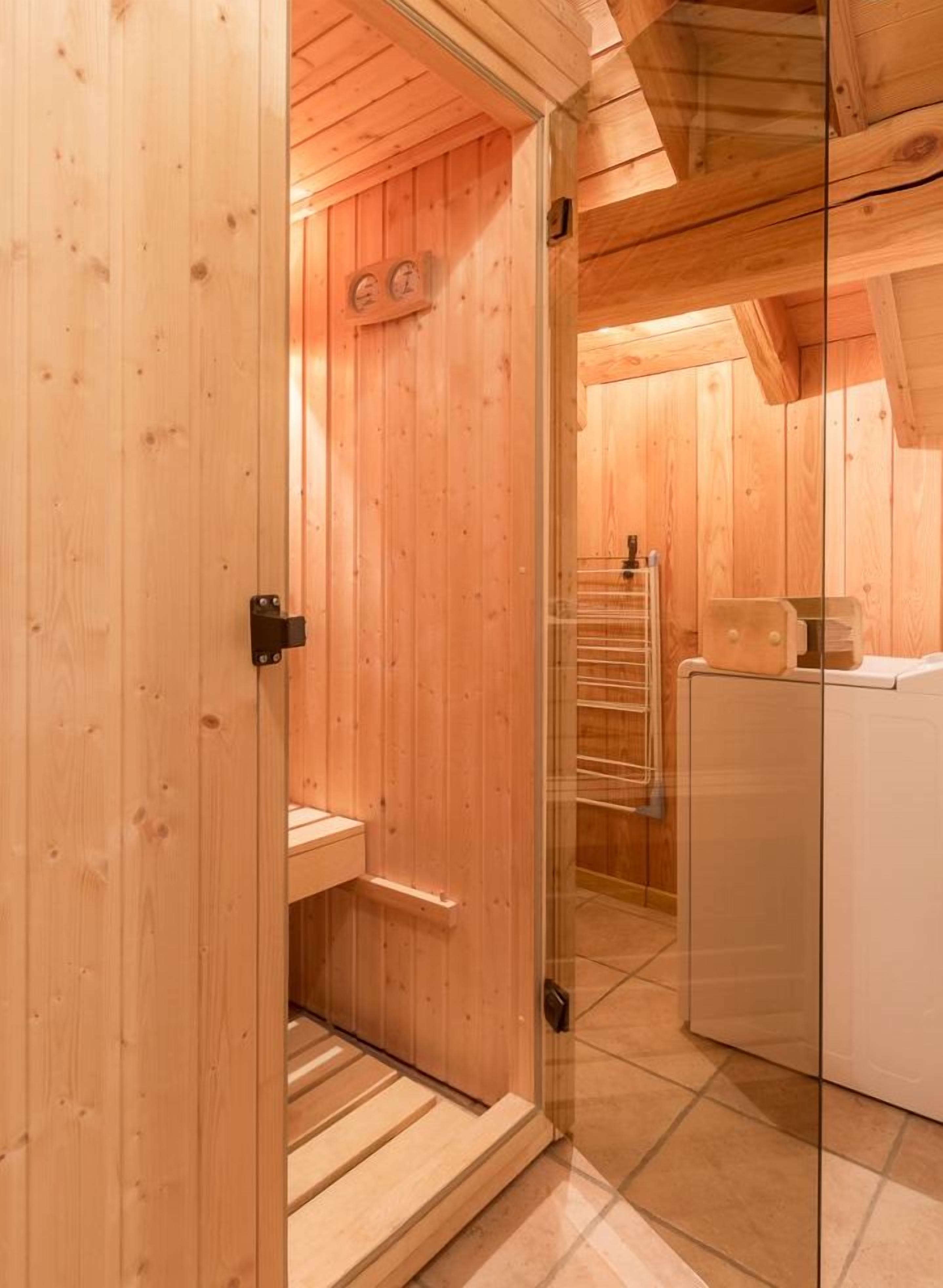 Un sauna en bois avec une porte en verre, un banc en bois et un porte-serviettes.