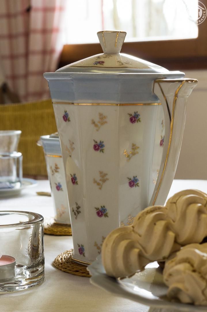 A table with a floral-patterned pitcher, a glass, and pastries.